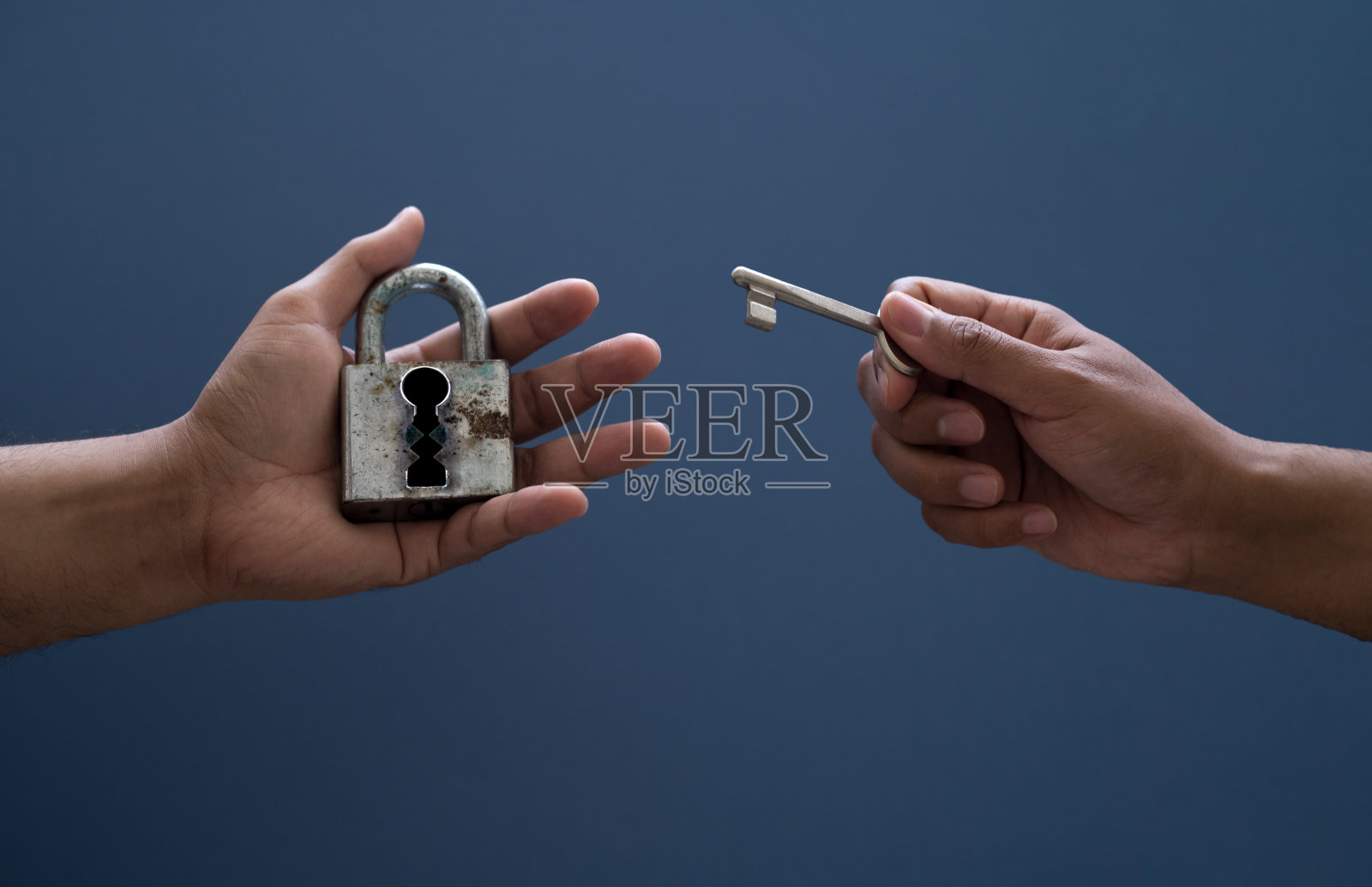 在孤立背景上握锁和钥匙的手。照片摄影图片