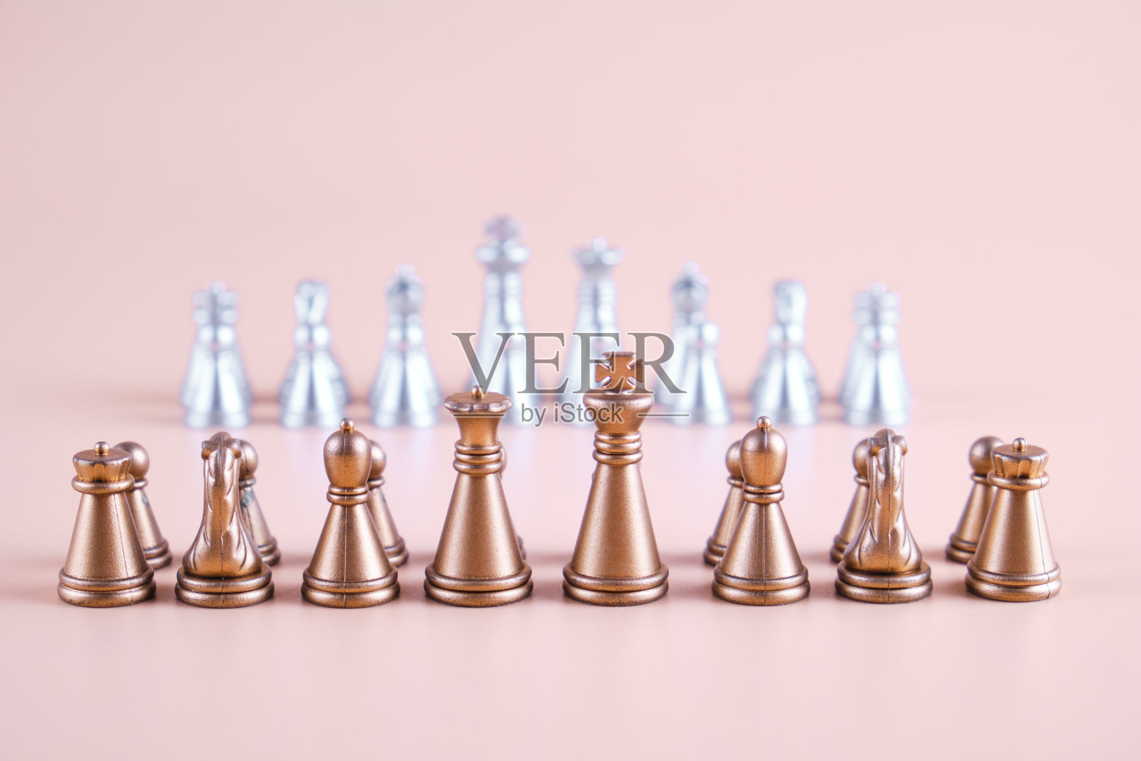 米色背景下的银棋前的金棋。照片摄影图片