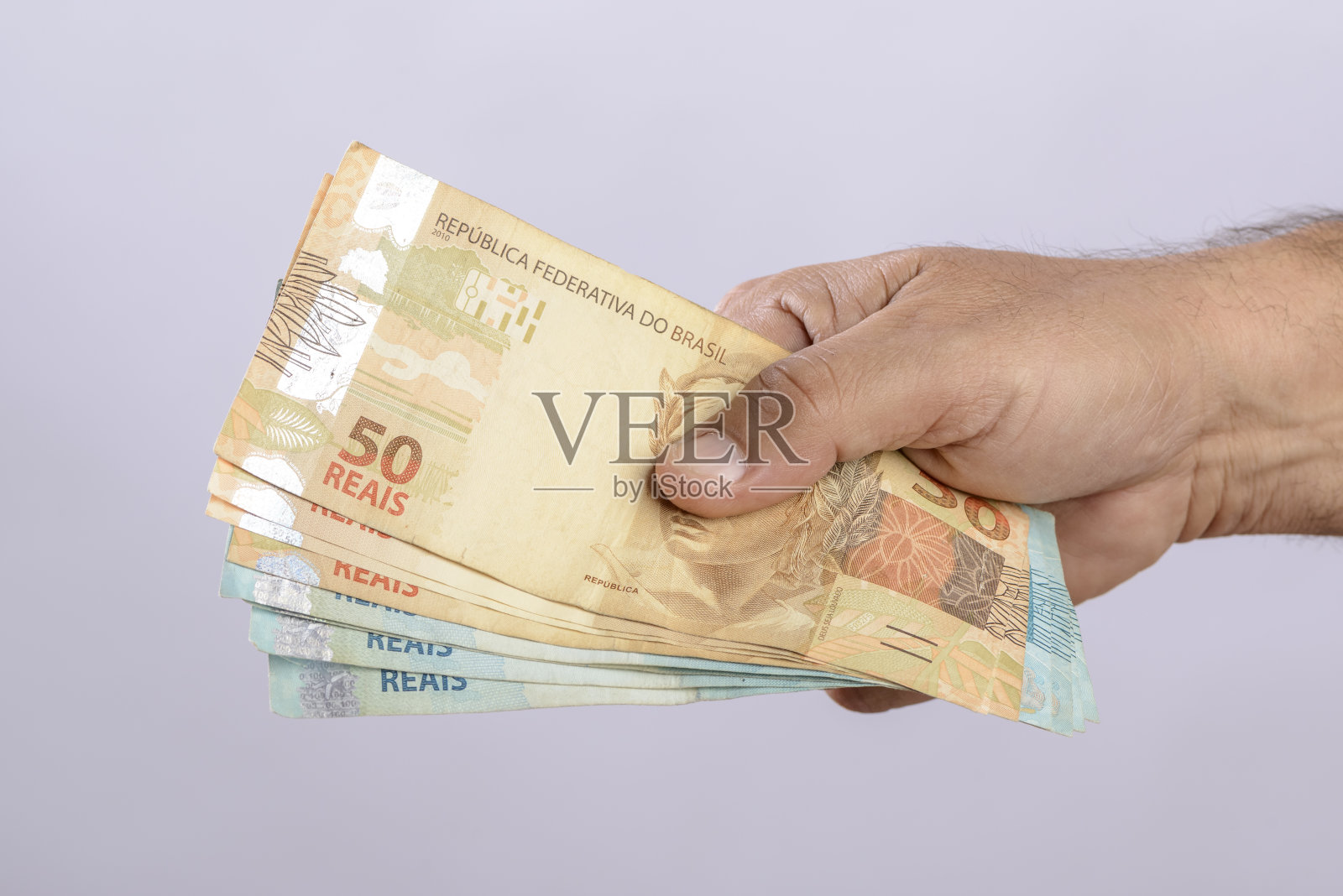 手里拿着钱，600雷亚尔，巴西货币，白色背景。照片摄影图片
