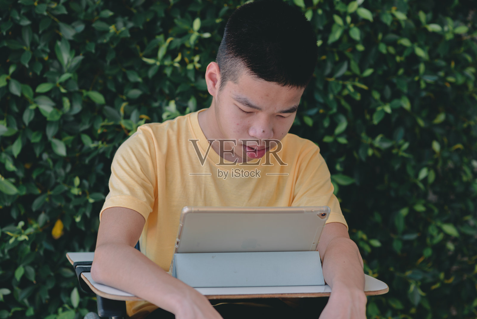 残疾人青年在轮椅上使用手机，科技为生活理念。照片摄影图片