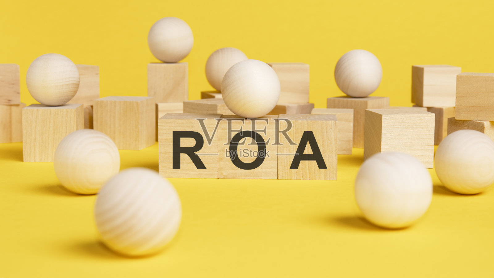 ROA写在木制立方体上。明亮的黄色表面。经营理念。木球球之间的木立方体，在市场概念上的不同和定位。ROA——资产回报率的缩写照片摄影图片