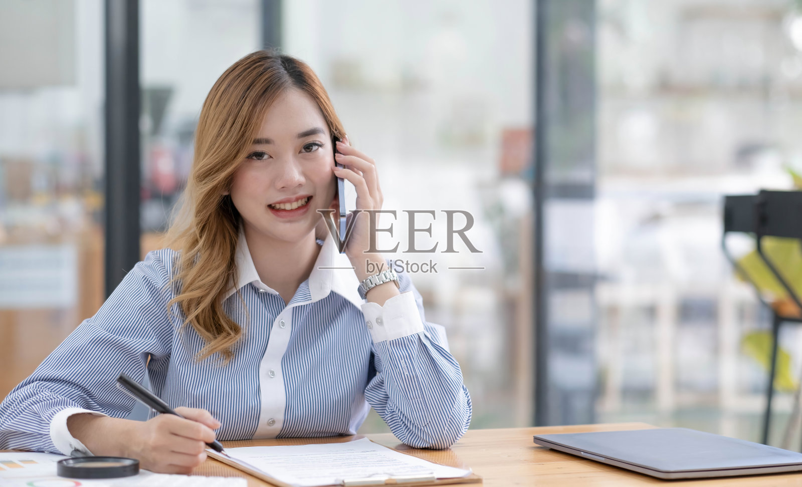 美丽的亚洲女商人在办公室工作时通过电话看相机照片摄影图片