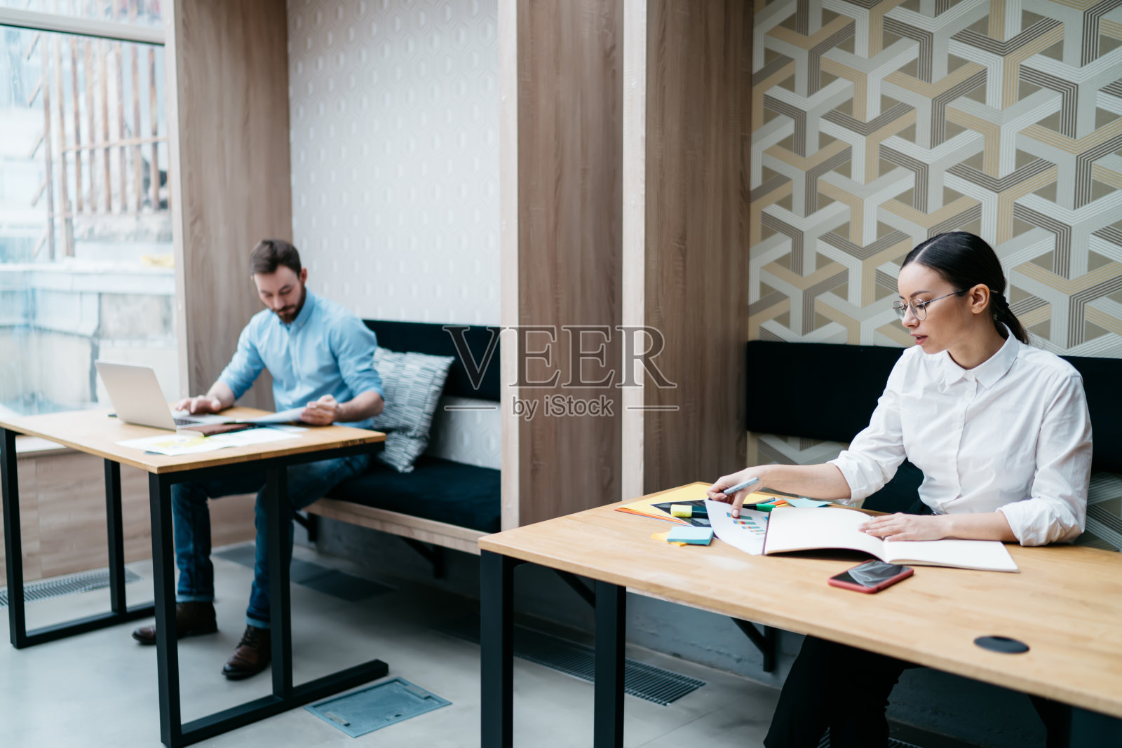 坐在旁边桌子上专心工作的同事照片摄影图片