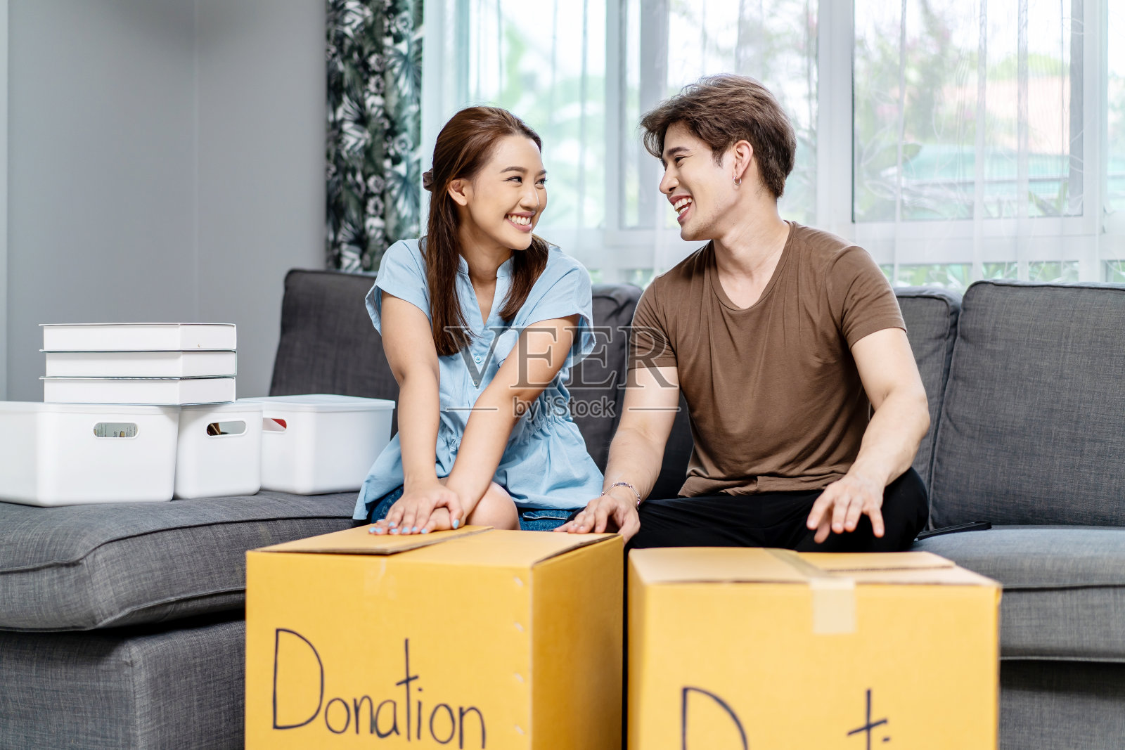 肖像一个快乐的年轻夫妇包装东西衣服，对象慈善纸箱，再利用捐赠，产品回收或志愿者分享捐赠的概念。照片摄影图片