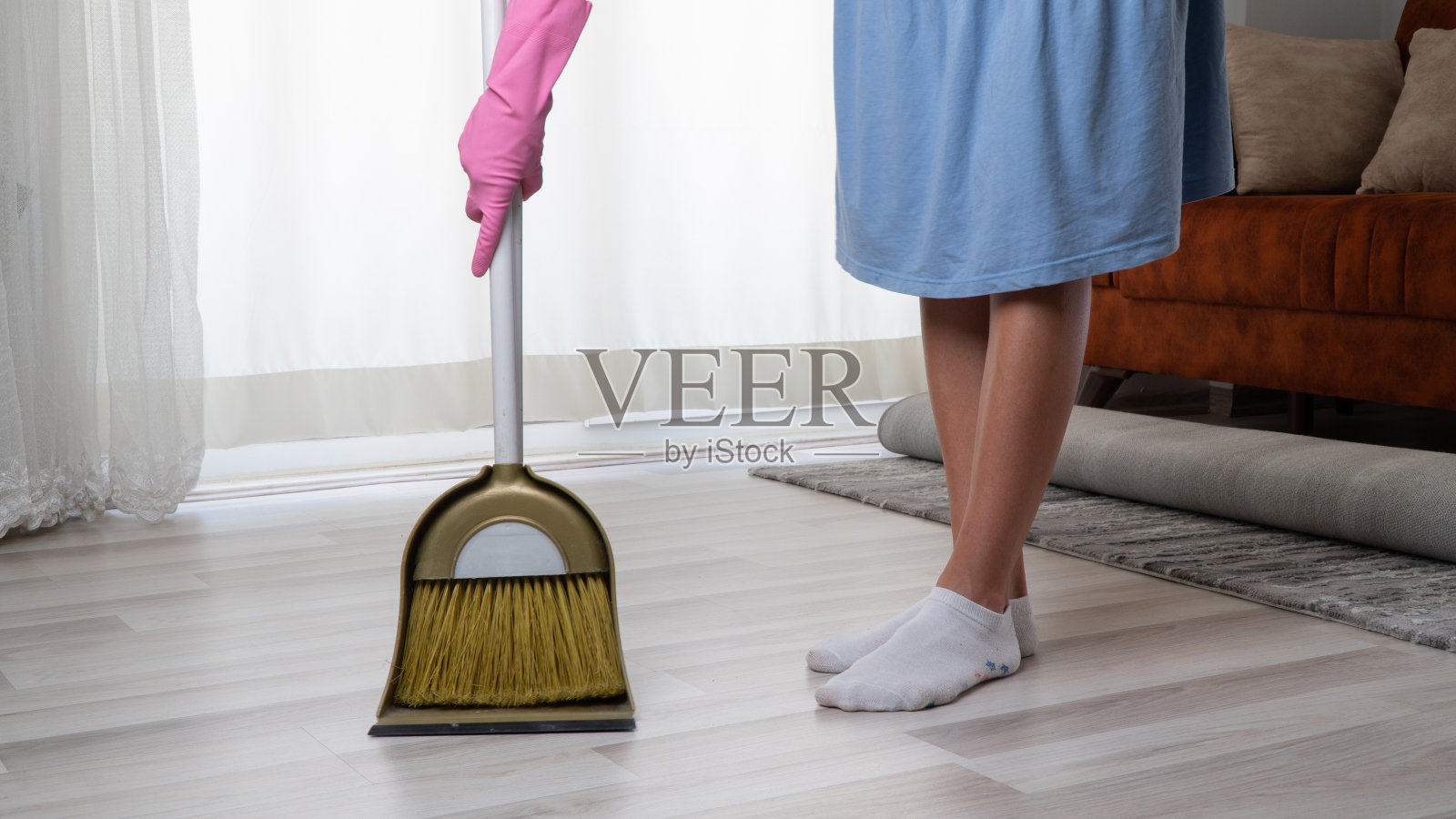 家庭主妇打扫屋子——用扫帚和簸箕扫地照片摄影图片