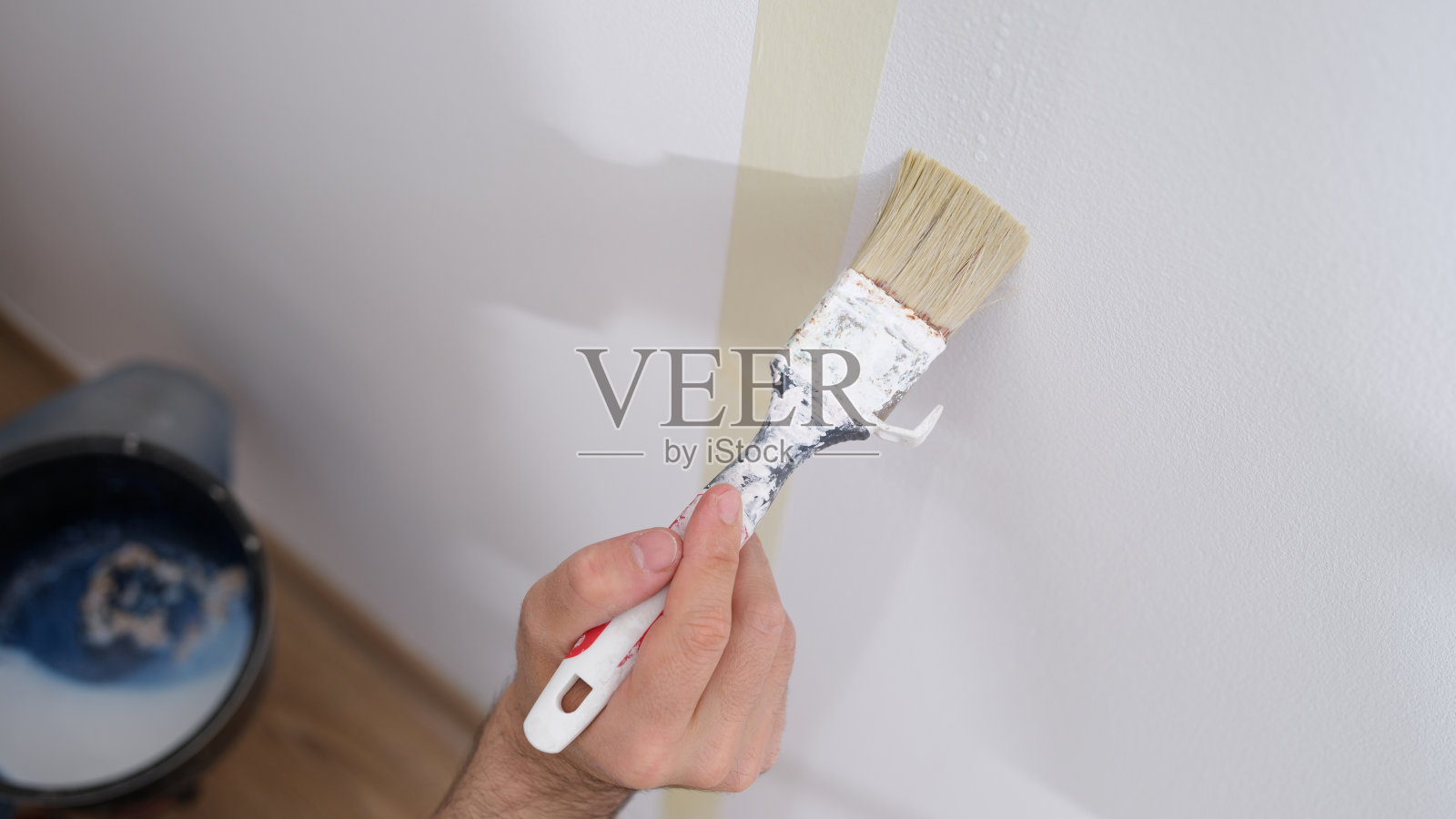 手工工人拿着刷子在房子的墙上刷白色照片摄影图片