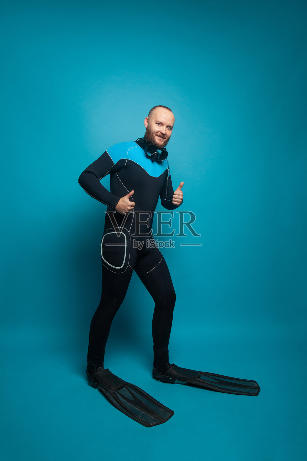 穿着潜水服的男人在蓝色背景上竖起大拇指照片摄影图片