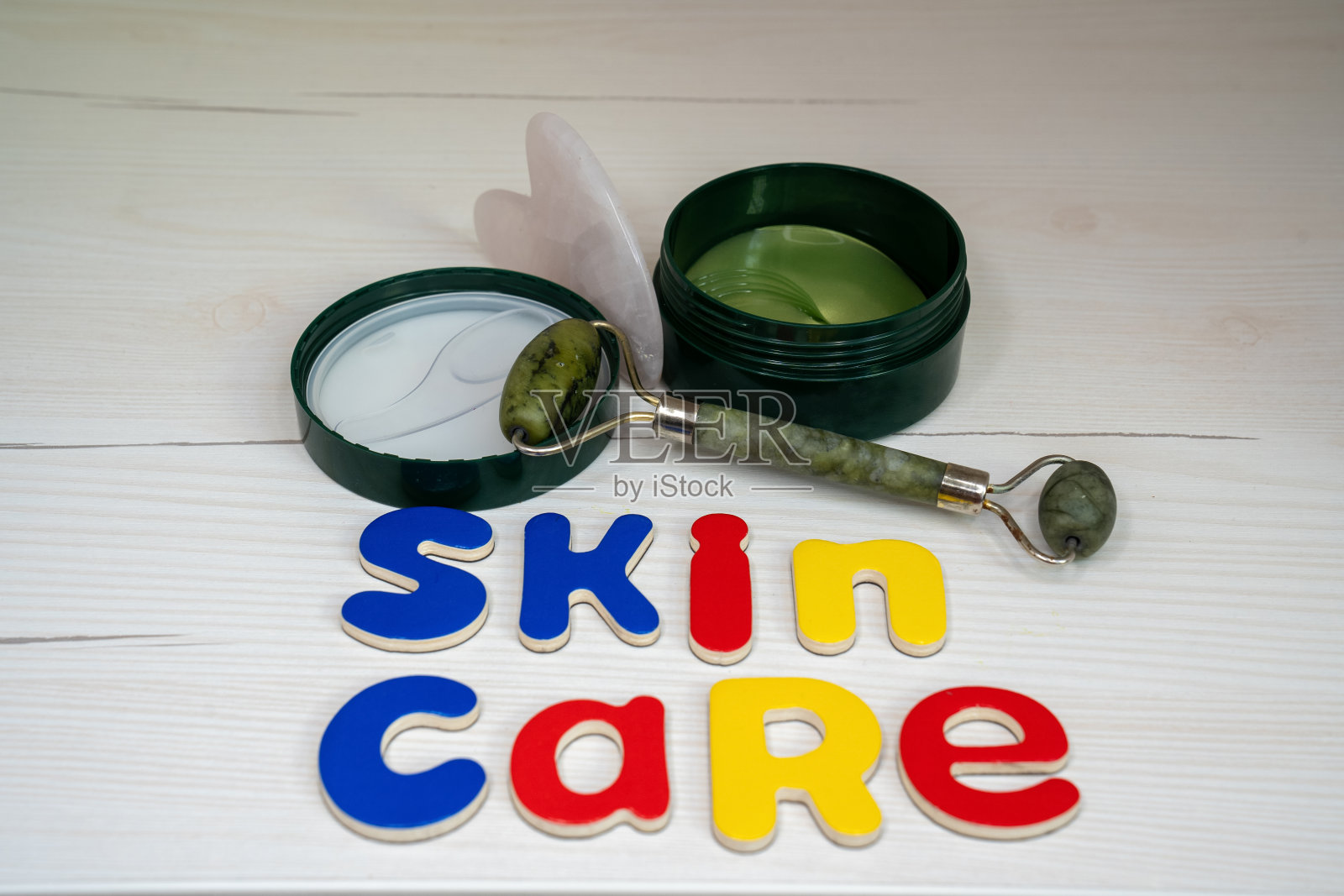 护肤配件刮痧滚轮美容工具，玉石滚轮旁膏眼罩和字护肤字母做成，美容院概念，面部治疗照片摄影图片