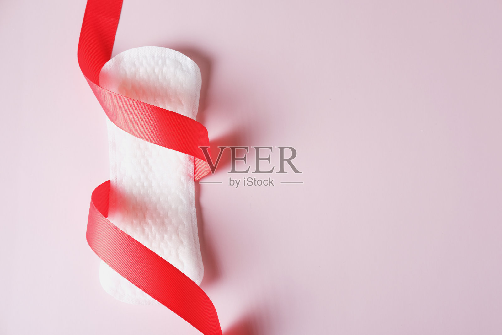 女性经期卫生巾，粉红色背景红丝带照片摄影图片