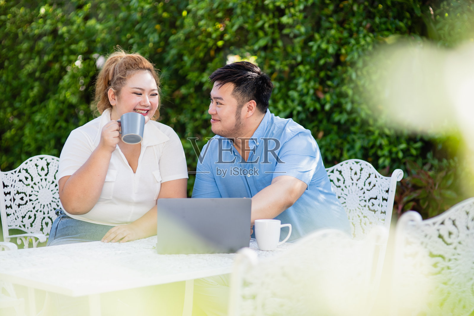 年轻的亚洲胖夫妇坐在院子里用笔记本电脑购买和网上购物照片摄影图片