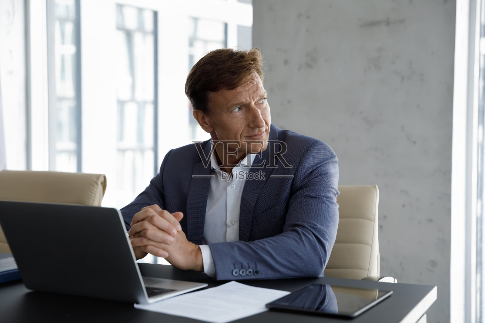 沉思，熟练的中年商人在电脑上工作。照片摄影图片