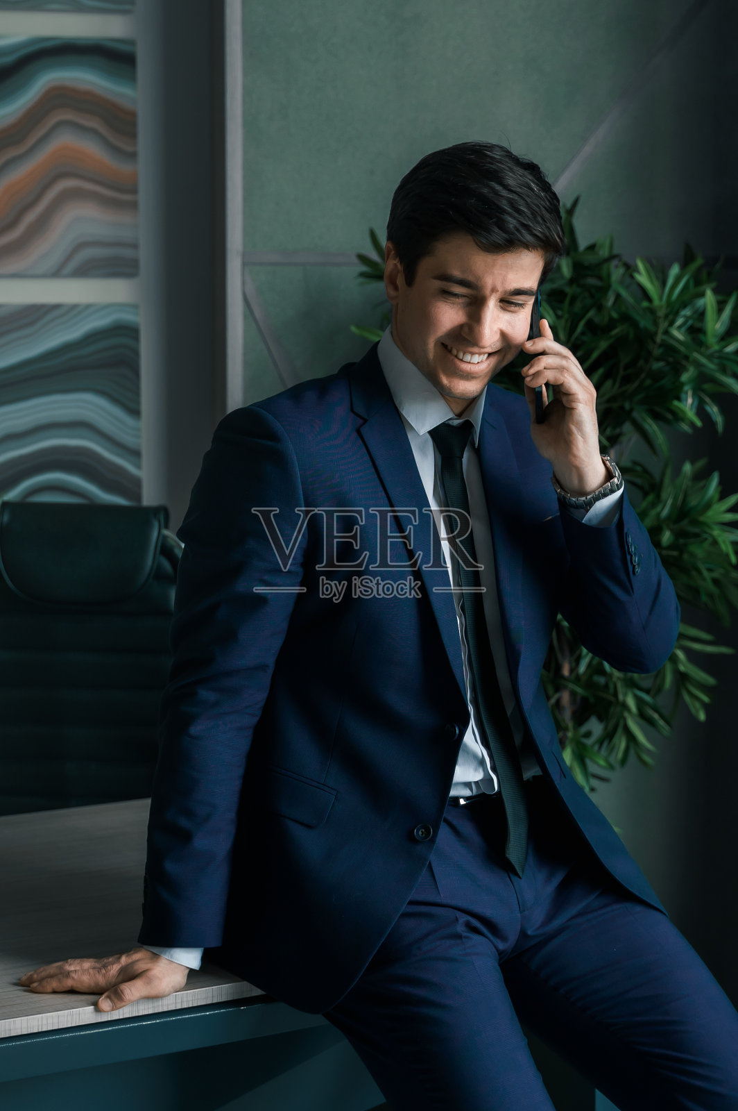 西装革履的商人，手里拿着手机。男人输入信息，使用社交网络。检查消息。商务会议。现代办公室。总经理、首席执行官。打电话来的合作伙伴。计划工作时间照片摄影图片