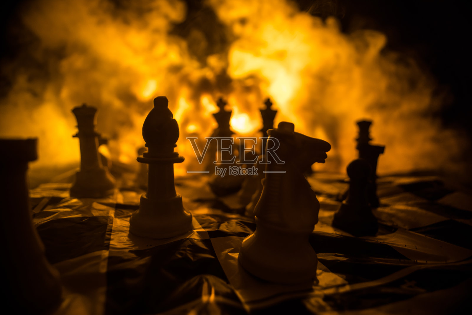 棋牌游戏概念有经营理念和竞争理念和战略理念。黑色背景上的象棋人物，烟雾缭绕。有选择性的重点照片摄影图片