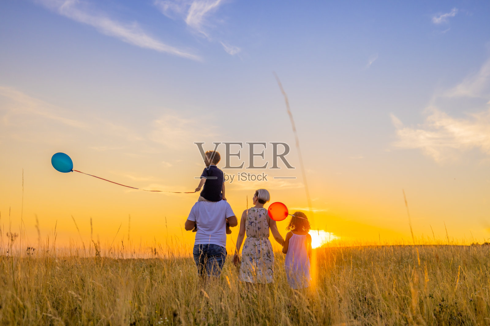 家庭散步，同时探索在草地日落照片摄影图片