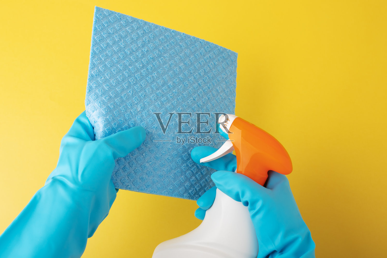 清洁服务时，双手拿着手套，在抹布上洒上一瓶洗衣液中的消毒喷雾照片摄影图片