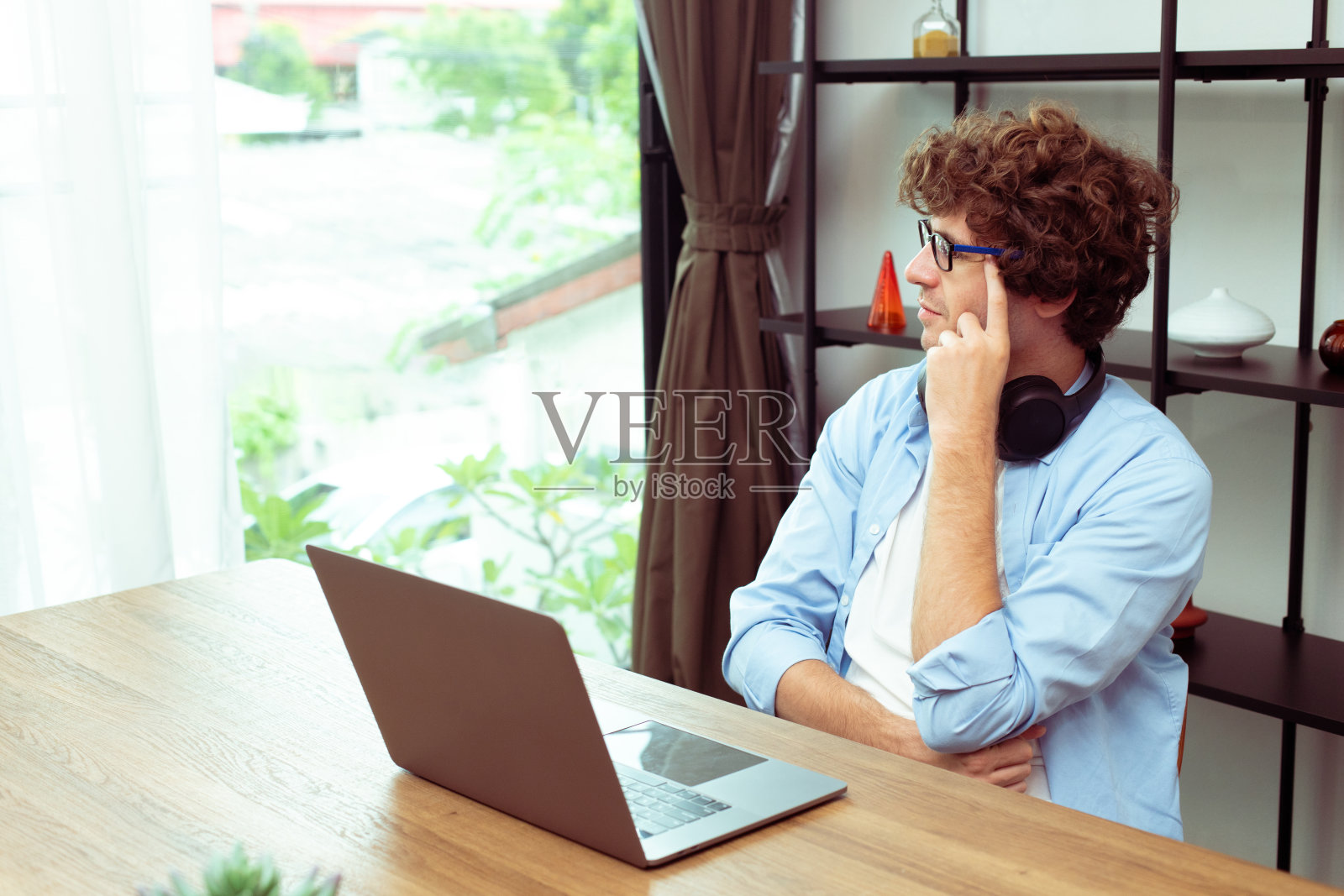 年轻的白人男子工作在家里的笔记本电脑，并连接到办公室的远程互联网工作室内。青年男性自由职业者在笔记本电脑上工作聪明地坐在工作间、复印空间照片摄影图片