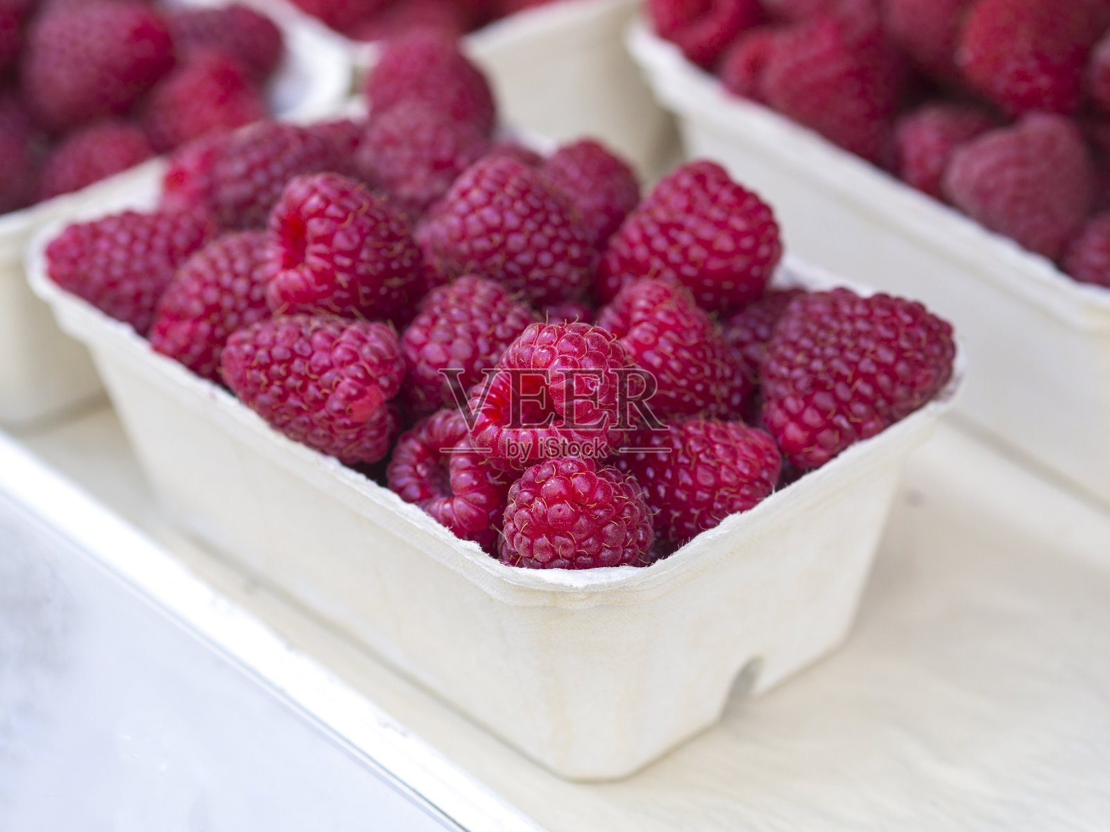 特写新鲜覆盆子在白色背景的白色纸盒照片摄影图片