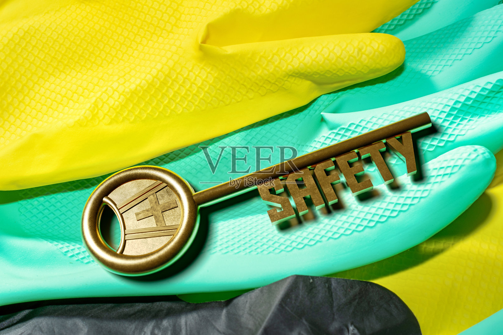 背景带防护手套和一把写有SAFETY字样的金钥匙。模板的主题是工作安全。照片摄影图片