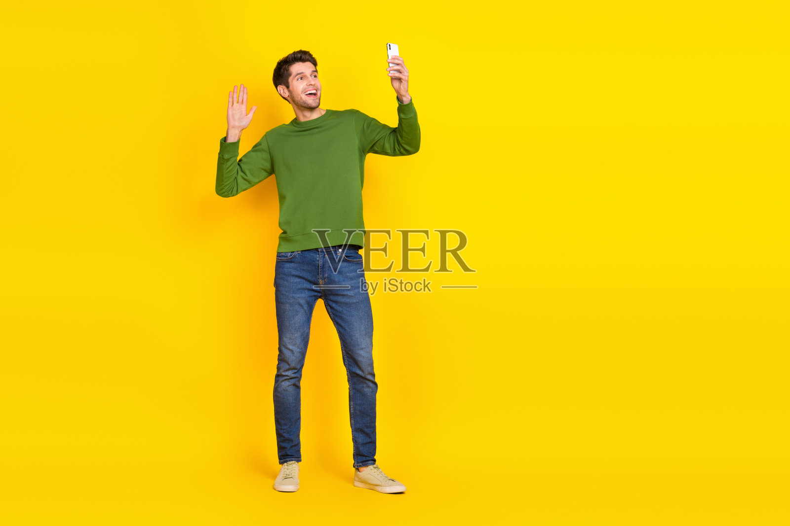 时髦兴奋的家伙穿绿色毛衣挥动手臂的照片照片现代小玩意空空间孤立的黄色背景照片摄影图片