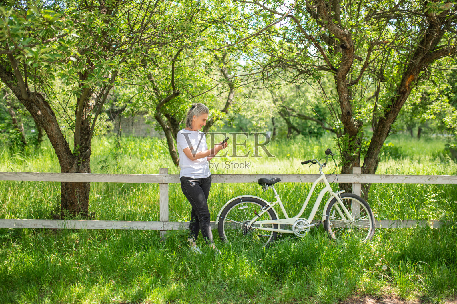一个骑着自行车的女人站在栅栏旁照片摄影图片