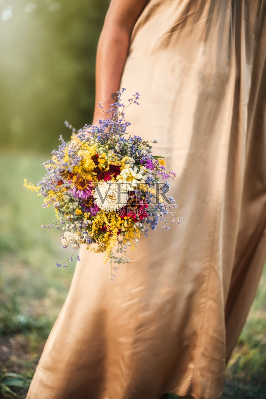 手里拿着一束野花。夏天的背景照片摄影图片