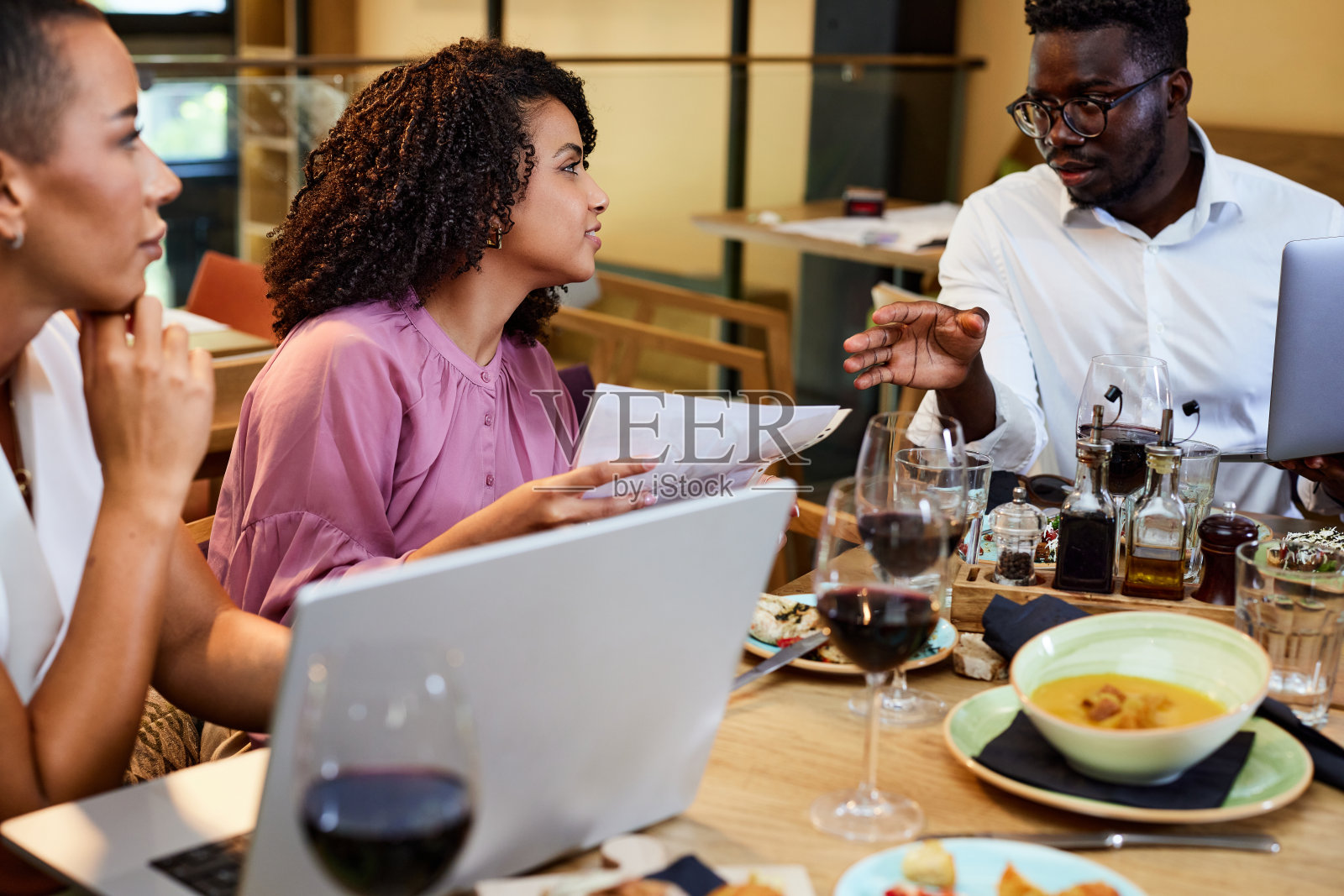 一位非洲普通商人在一家餐馆的餐桌上为他的同事们做演示。照片摄影图片