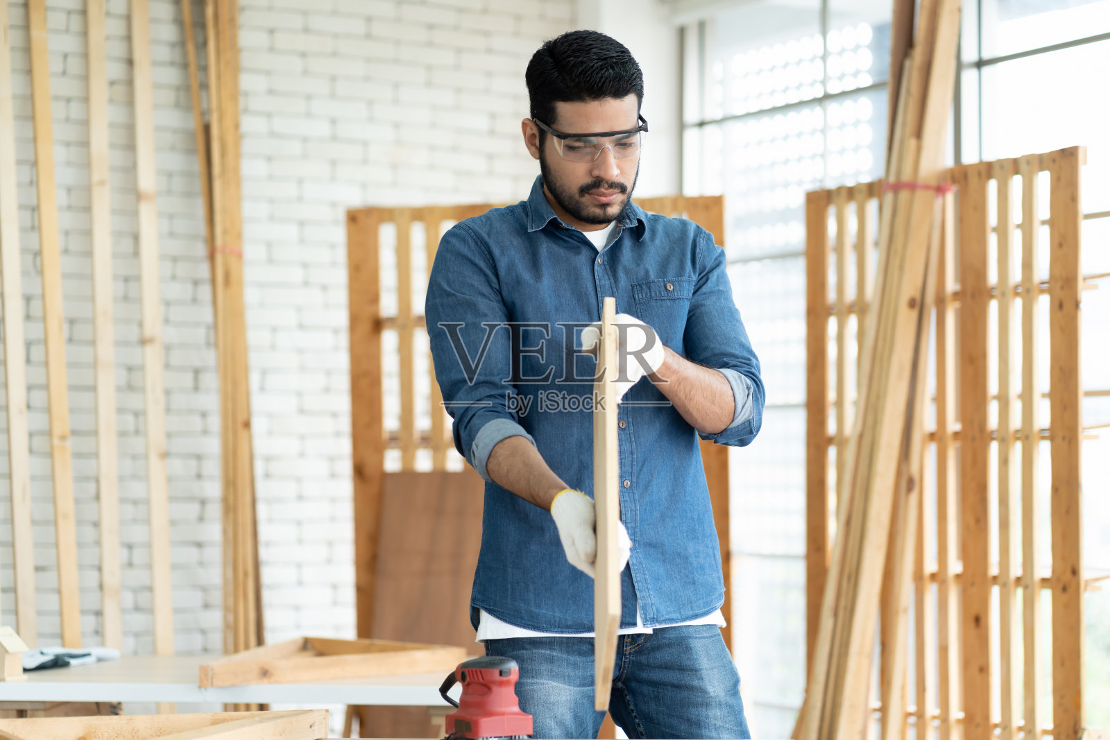 木工工人在木工车间工作和检查木工家具。亚洲男性木工工人戴安全设备工具在木工车间工作照片摄影图片