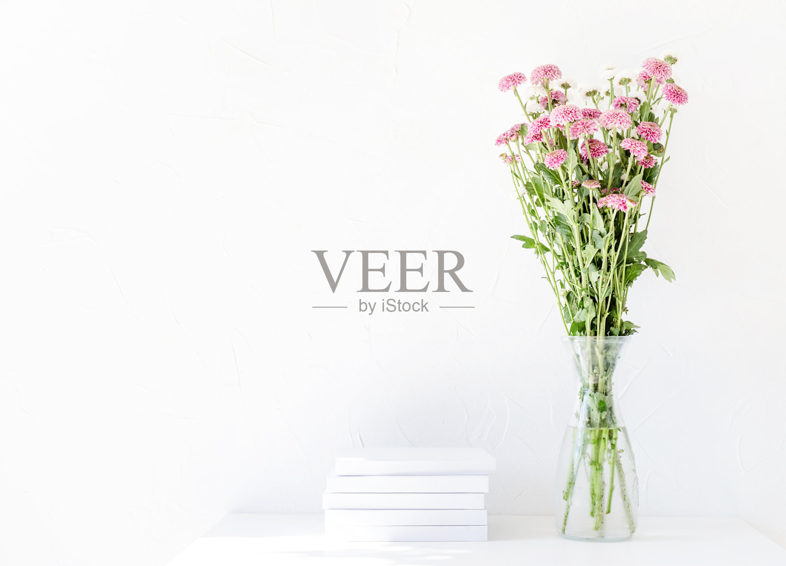 白色的书模型与菊花在一个白色的桌子上的花瓶照片摄影图片