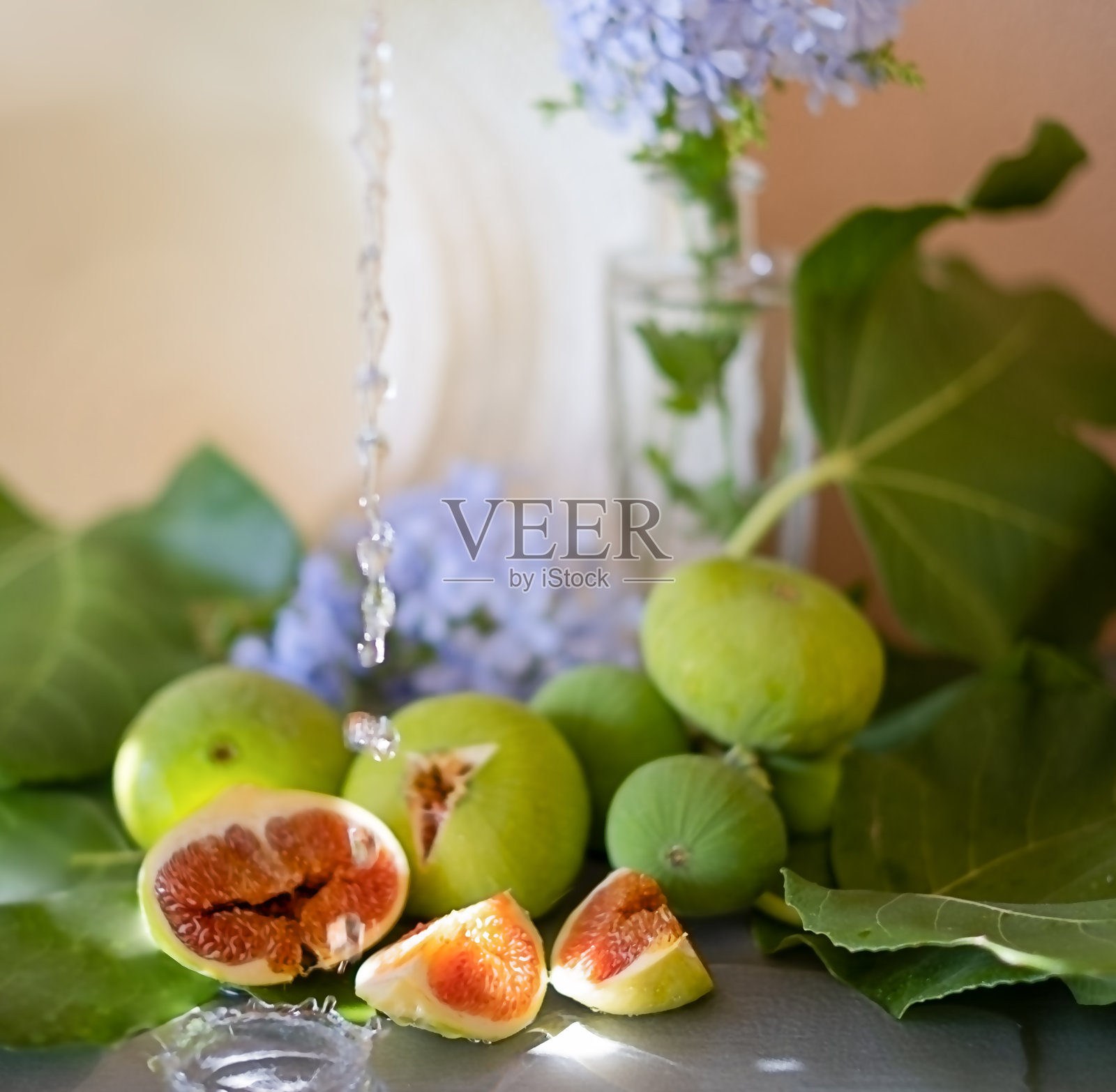 收获无花果时，有水流，有树叶，米色背景上有蓝色花朵的玻璃花瓶照片摄影图片
