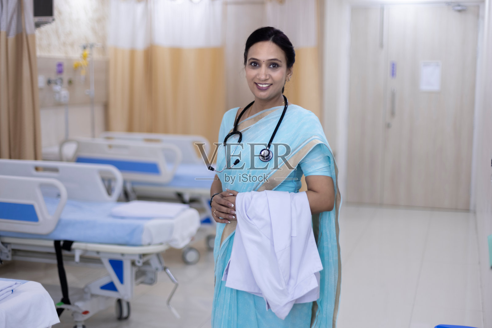 自信微笑的医生穿着纱丽站在医院病房的肖像照片摄影图片