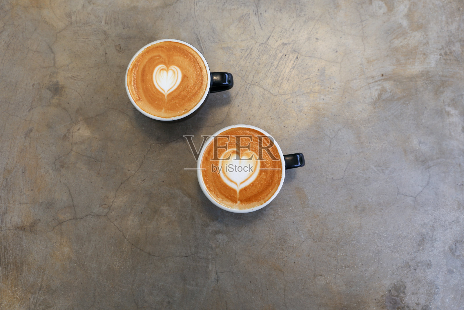 混凝土背景上两杯热卡布奇诺。心形艺术拿铁象征爱情。照片摄影图片