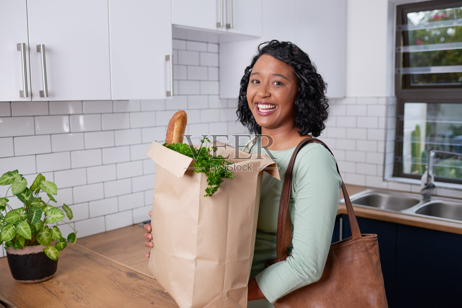 一个年轻的多种族妇女带着纸袋从杂货店购物回家照片摄影图片