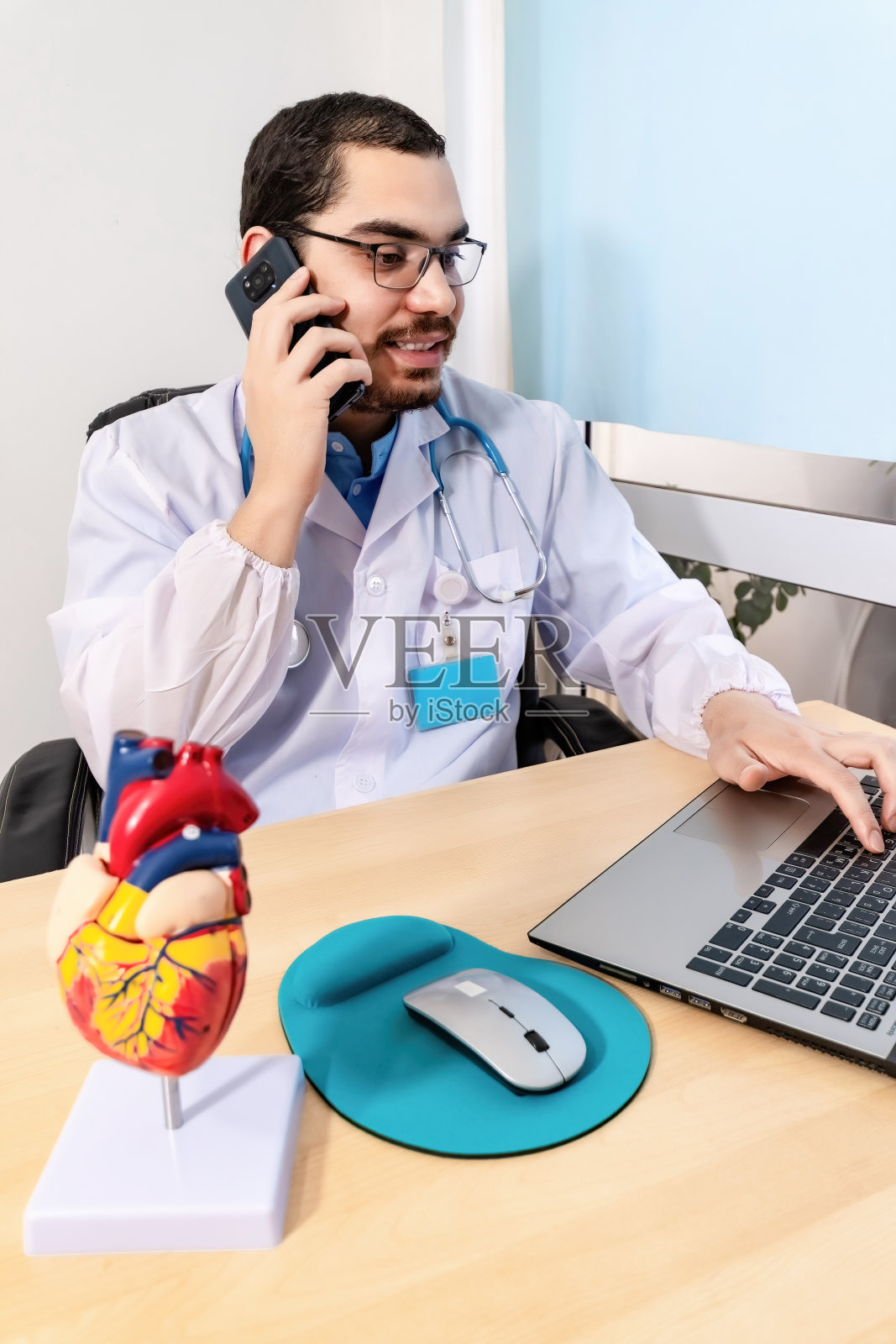 在办公室使用笔记本电脑打电话的医生照片摄影图片