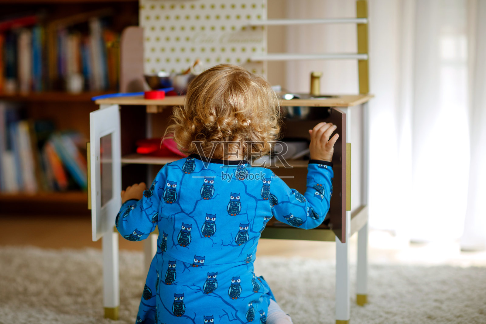 可爱可爱的蹒跚学步的小女孩玩玩具厨房快乐健康的婴儿孩子玩角色游戏，在家里或托儿所玩陶器茶壶。活泼的女儿和玩具。照片摄影图片