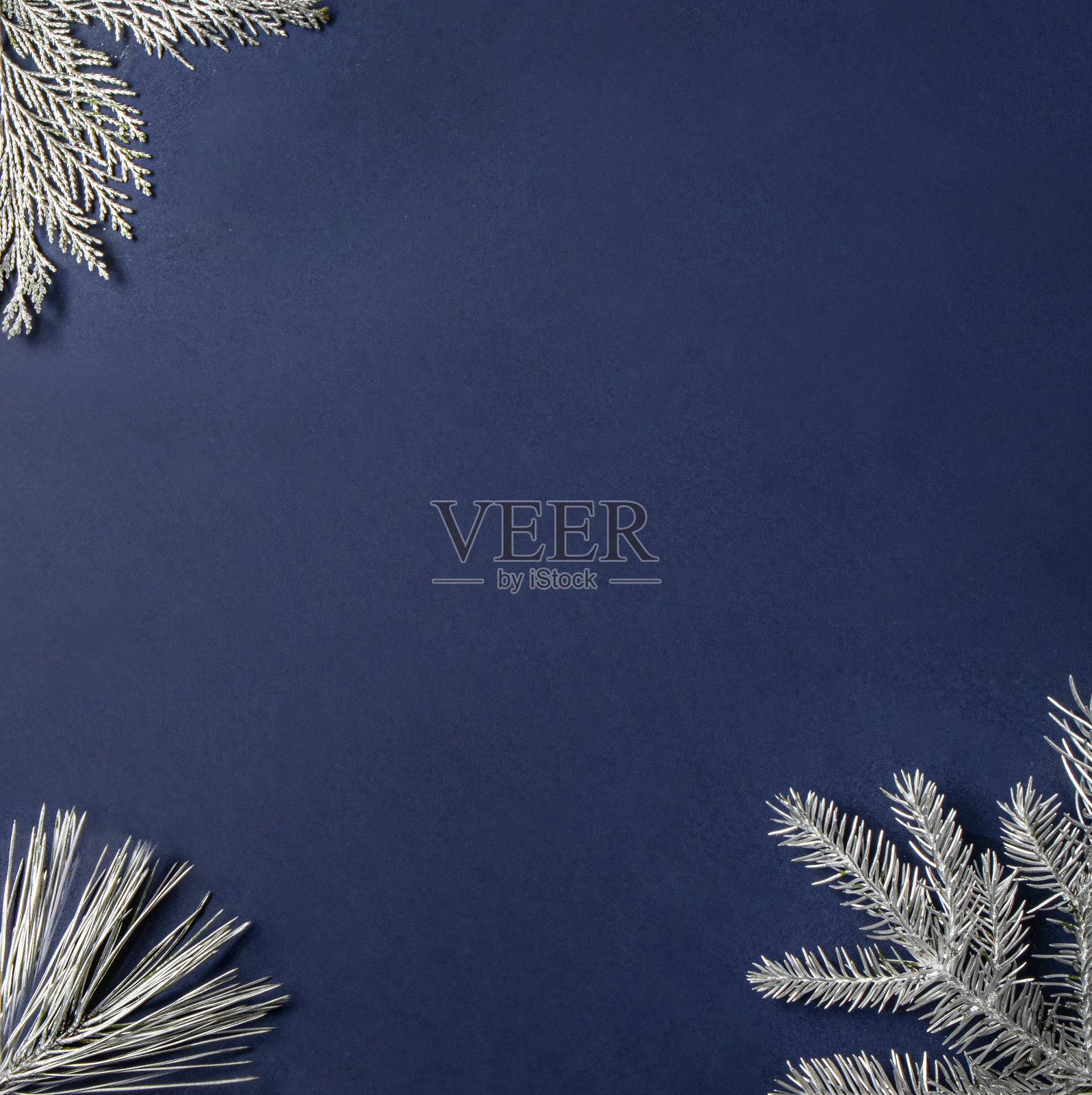 银色霜冻的圣诞树枝框架在深蓝色的背景。寒冬腊月节夜概念。简约的圣诞装饰理念。传统新年平铺构图。照片摄影图片