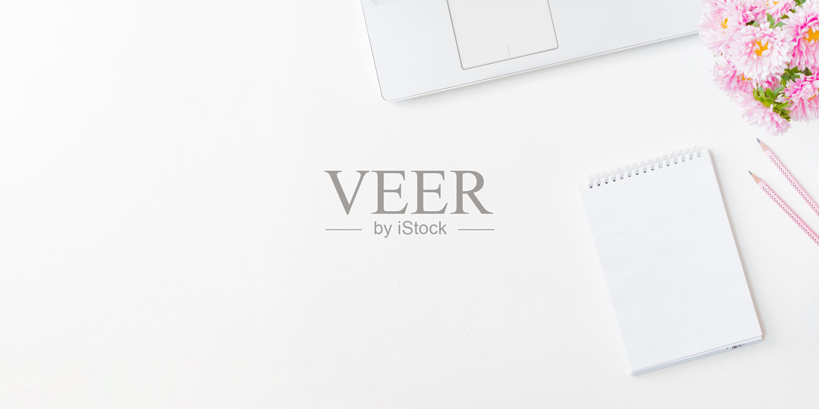 俯视图家庭办公桌面与笔记本电脑，粉红色的花在一个花瓶，笔记本，办公用品在一个浅色的背景。平铺模型空白笔记本页。带有复制空间的横幅背景照片摄影图片