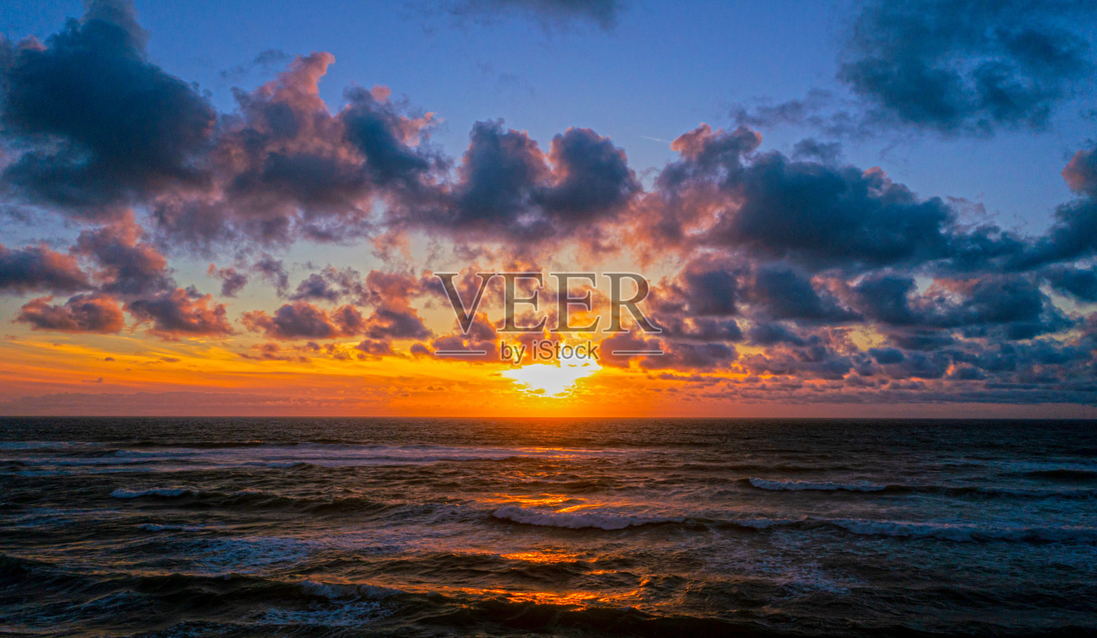 美丽的海景，在地平线上，太阳在水面上。无人机近距离观察海面日落。航拍巨浪与天际线。放松和冥想照片摄影图片