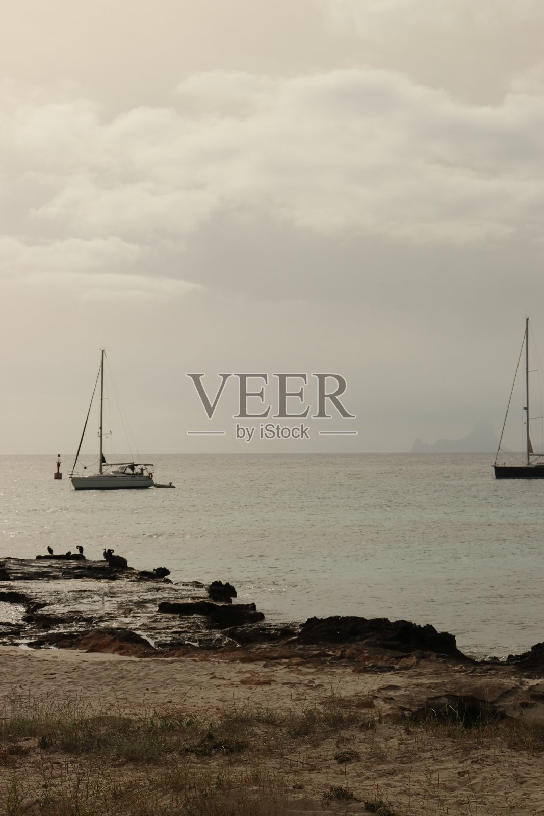 福门特拉岛上的两艘帆船，在一个多云的日落中。垂直的图像。照片摄影图片