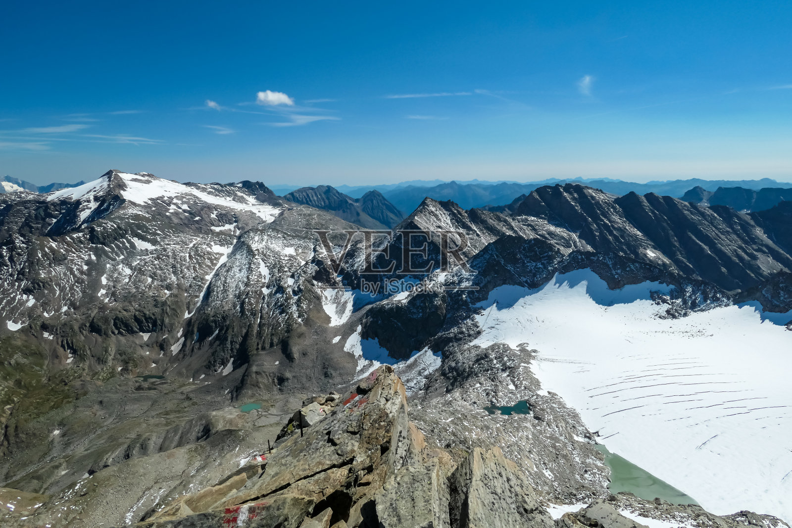 Hoher Sonnblick -一名活跃的男子站在一块岩石上，可以看到奥地利萨尔斯堡卡林西亚的Hoher Sonnblick冰川照片摄影图片