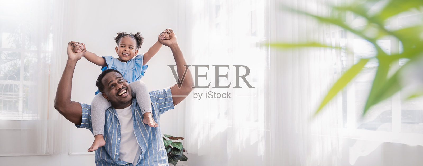 快乐的黑人非洲裔美国父亲和女儿在他们家的客厅里玩耍。非洲裔美国人抱着蹒跚学步的女孩。欢乐的家庭团结在一起，爸爸。T.带有复制空间的概念横幅照片摄影图片