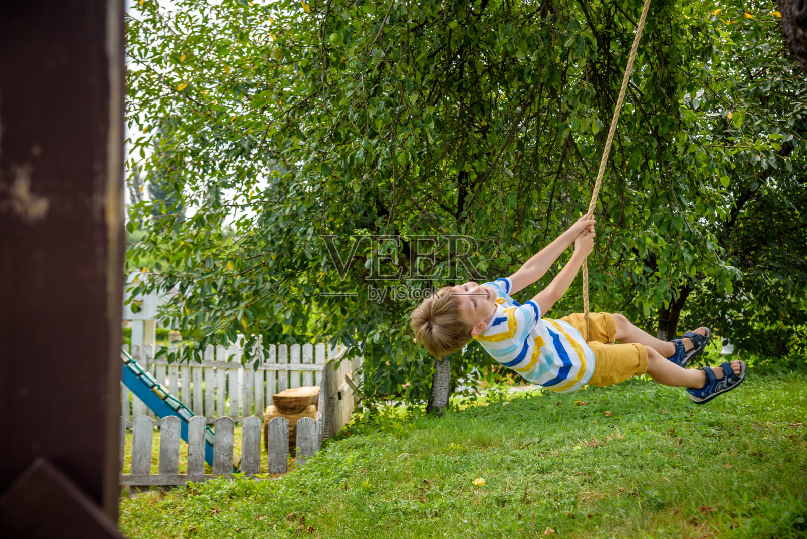 一个快乐的小男孩在秋千上玩得很开心，这是他在城外休息时发现的。与孩子们一起度过积极的休闲时光照片摄影图片