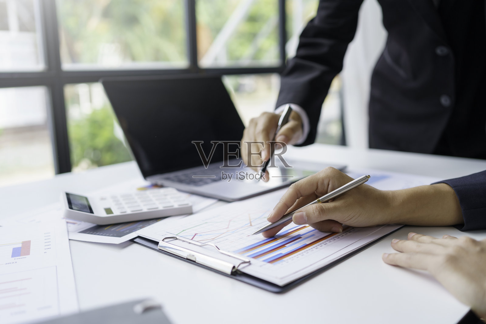 商务人士开会讨论市场投资分析的想法，他们在办公室里指着这张图。照片摄影图片