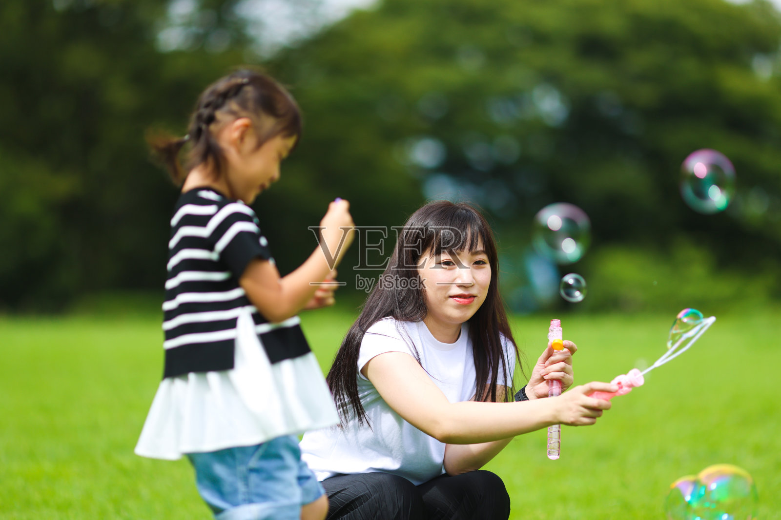 妈妈和女儿在公园里玩肥皂泡照片摄影图片