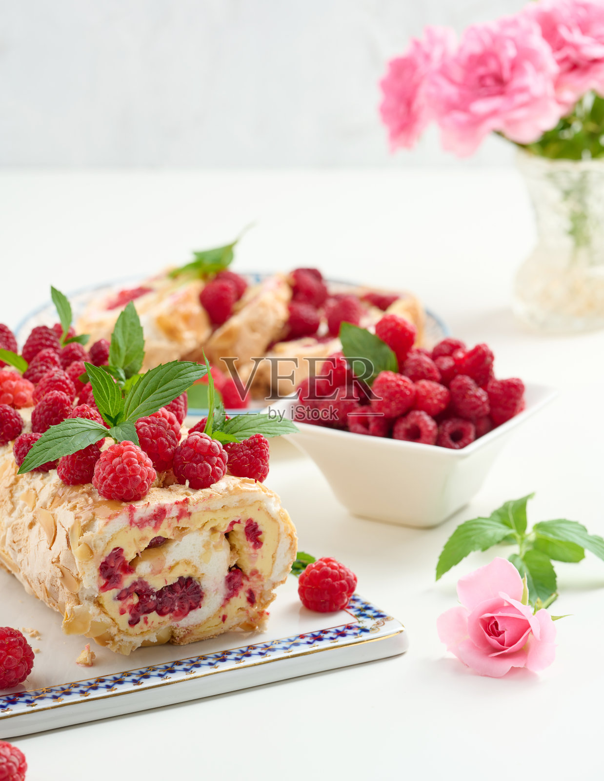 烤蛋白霜卷配鲜奶油和鲜红覆盆子放在白板上照片摄影图片