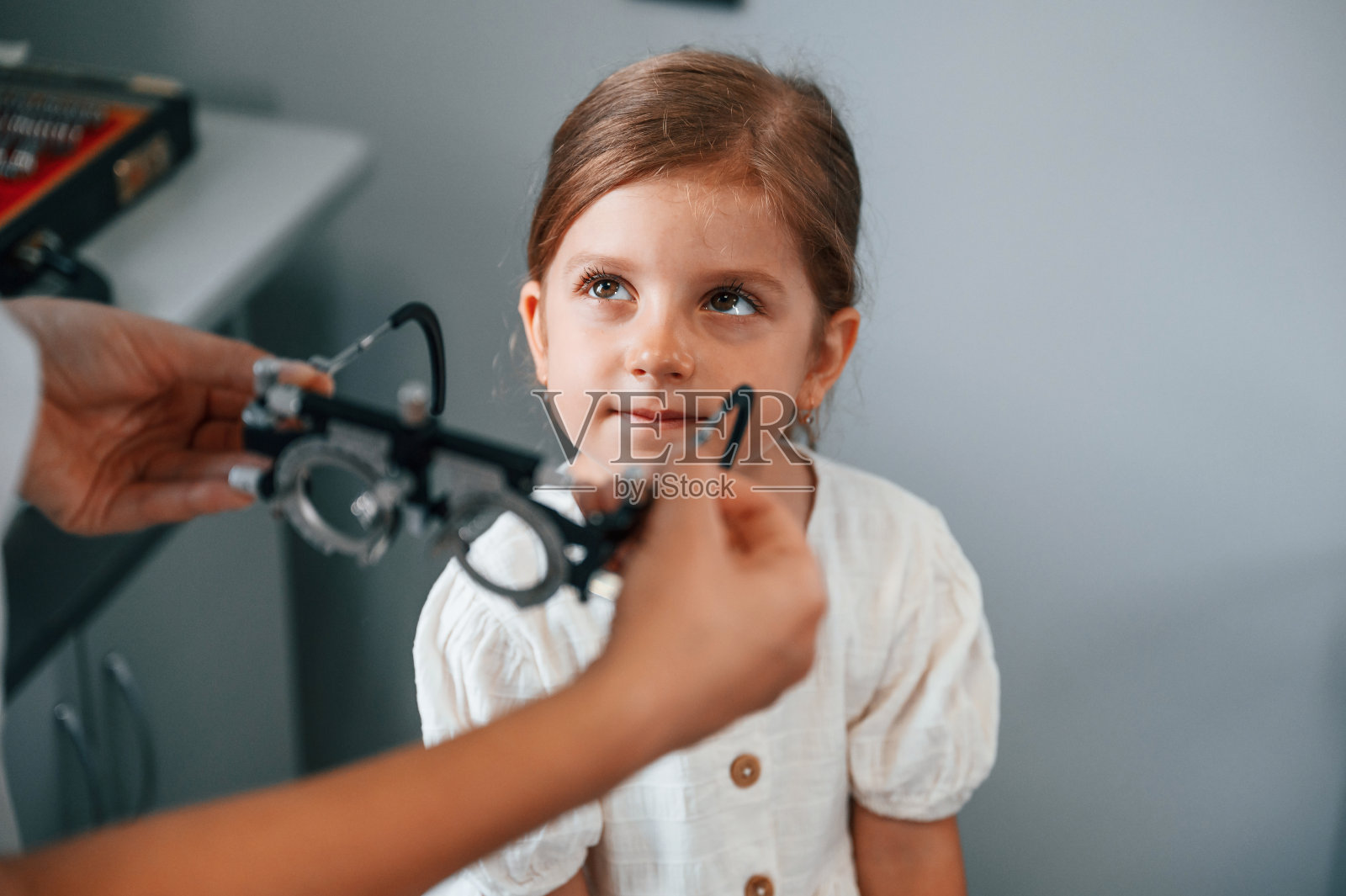 在特殊的装置与镜头。小女孩在女医生的帮助下在诊所检查视力照片摄影图片