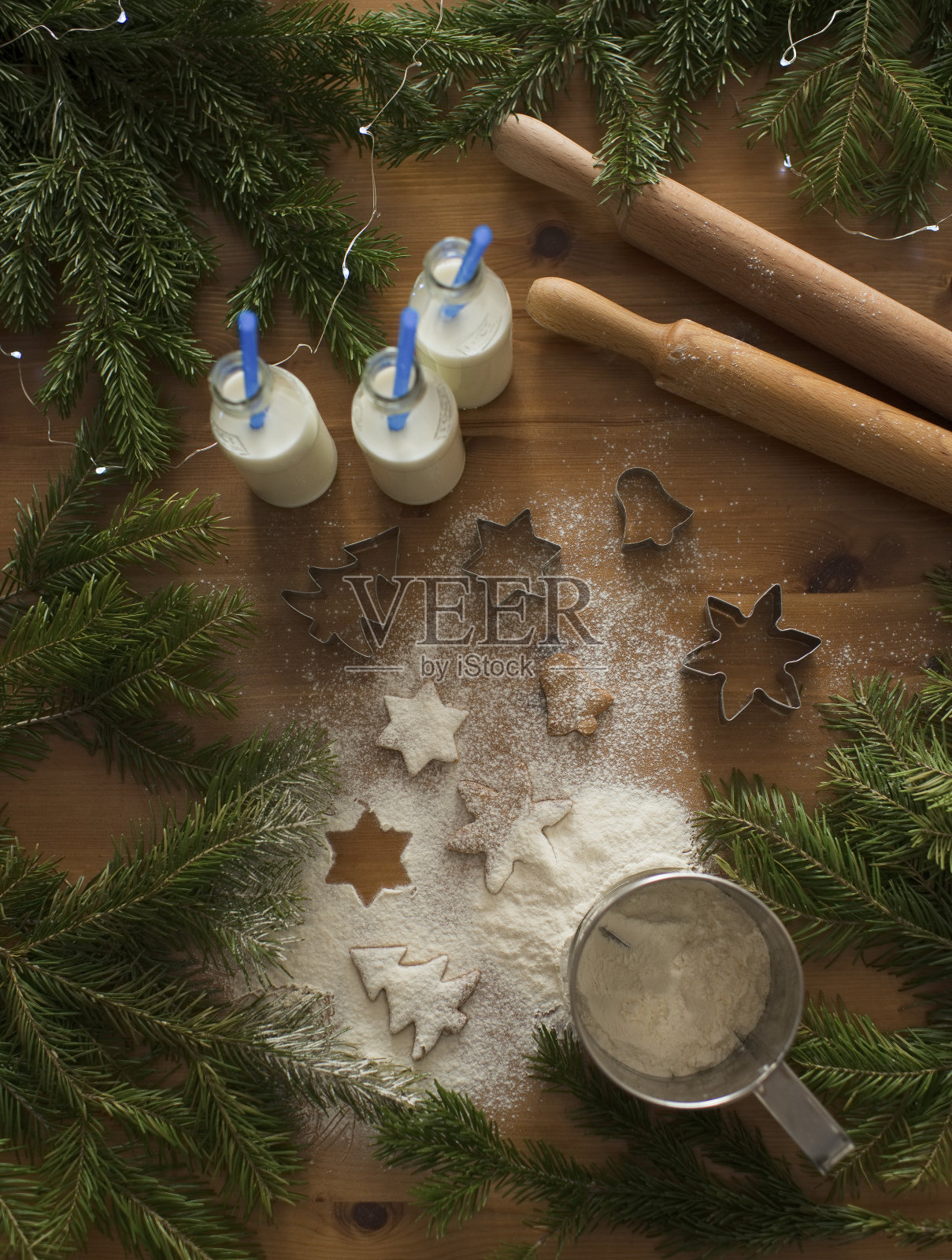 桌上放着姜饼和撒撒的面粉，还有针叶树枝照片摄影图片