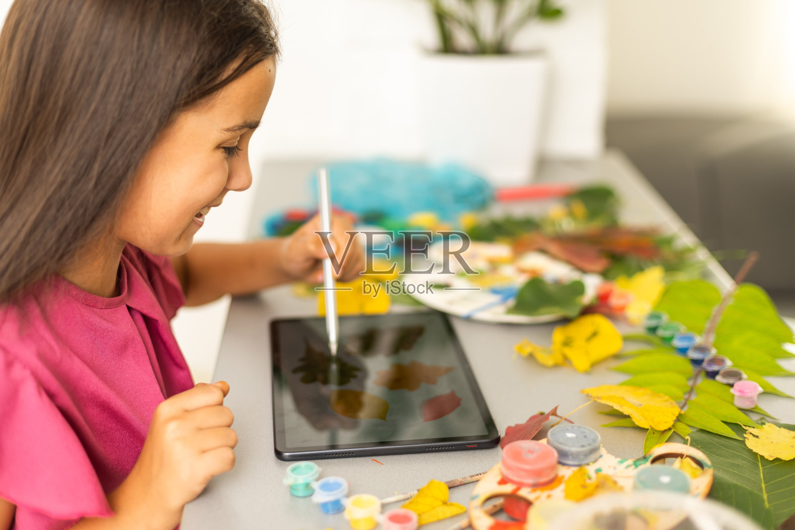 小女孩在家里用毛笔画树叶，秋天的艺术。照片摄影图片