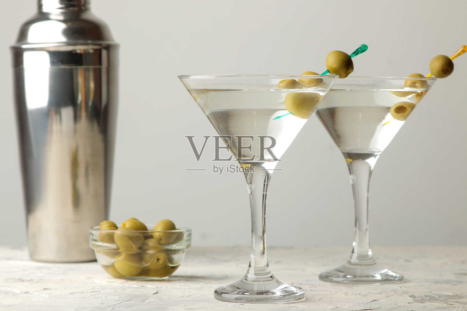 马提尼。酒精饮料马提尼加橄榄在一个杯子里，在酒吧柜台上的一个明亮的背景。酒吧库存。鸡尾酒照片摄影图片