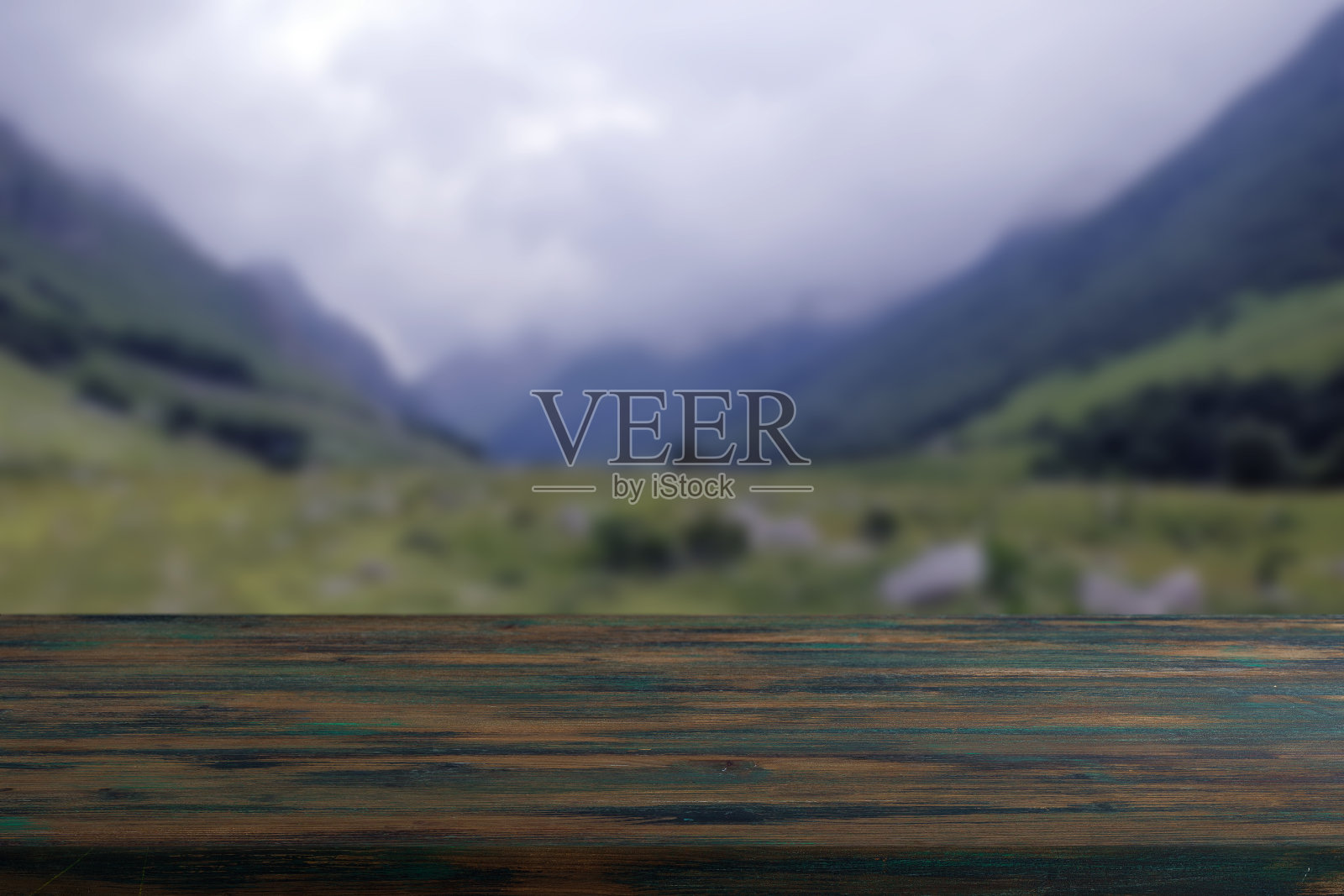木板空桌子前面模糊的背景。棕色的树林在模糊的山脉背景之上照片摄影图片