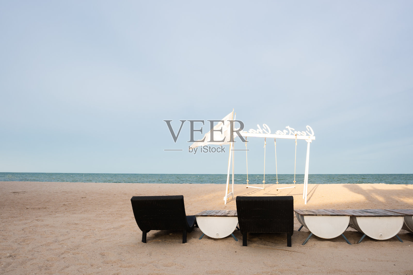 白色的沙滩，白色的椅子和秋千，蓝色的天空。照片摄影图片